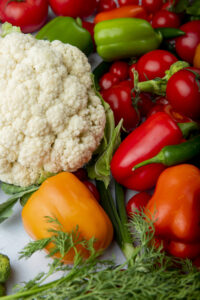 top view of fresh ripe vegetables cauliflower tomatoes colorful bell peppers and green chili pepper on white background